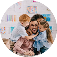 male teacher being hugged by kindergarten students