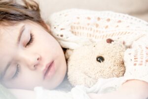 a girl sleeping while hugging a stuffed toy